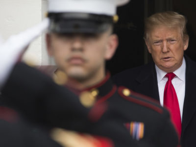 Donald Trump stands in a shadowy doorway