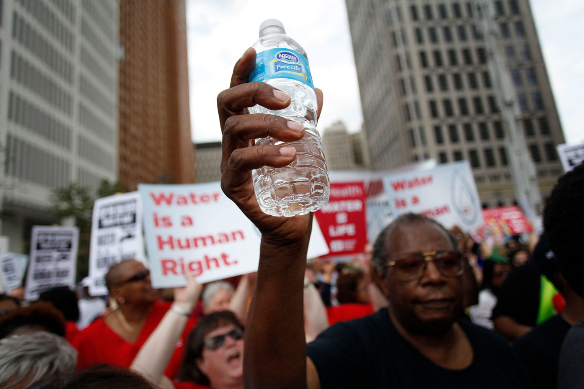 Man holding water bottle joins others protesting Detroit Water and Sewer Department