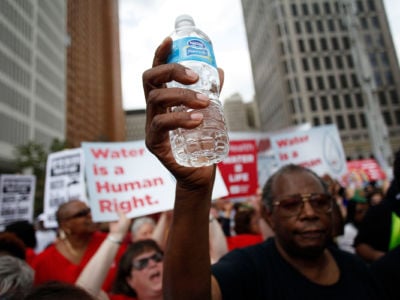 Man holding water bottle joins others protesting Detroit Water and Sewer Department