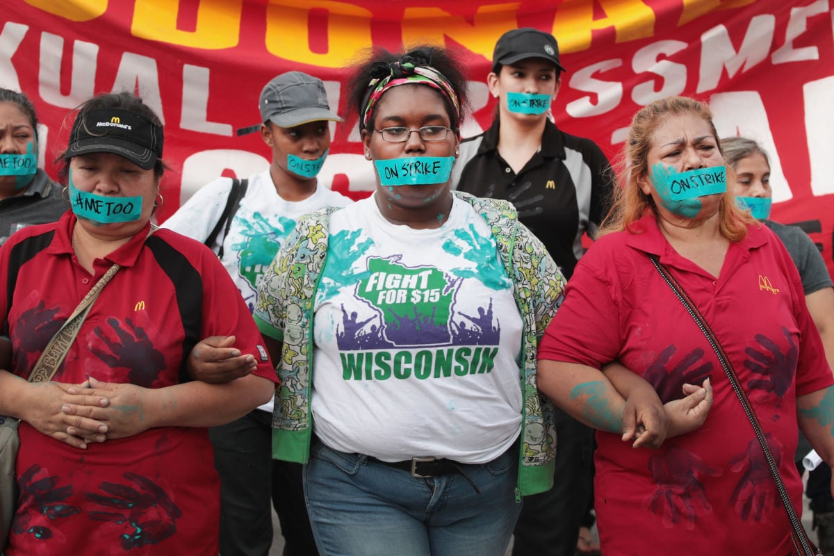 Women with blue tape over their mouths link arms during protest march