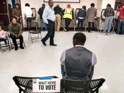 A Black man waits to vote as others stand in a line in front of him