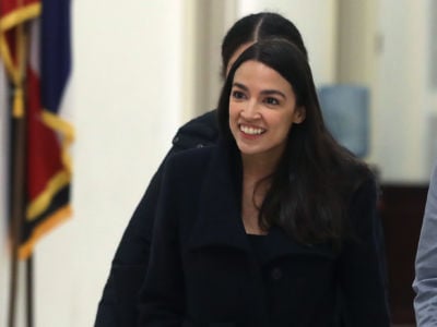 Rep. Alexandria Ocasio-Cortez smiles in a hallway