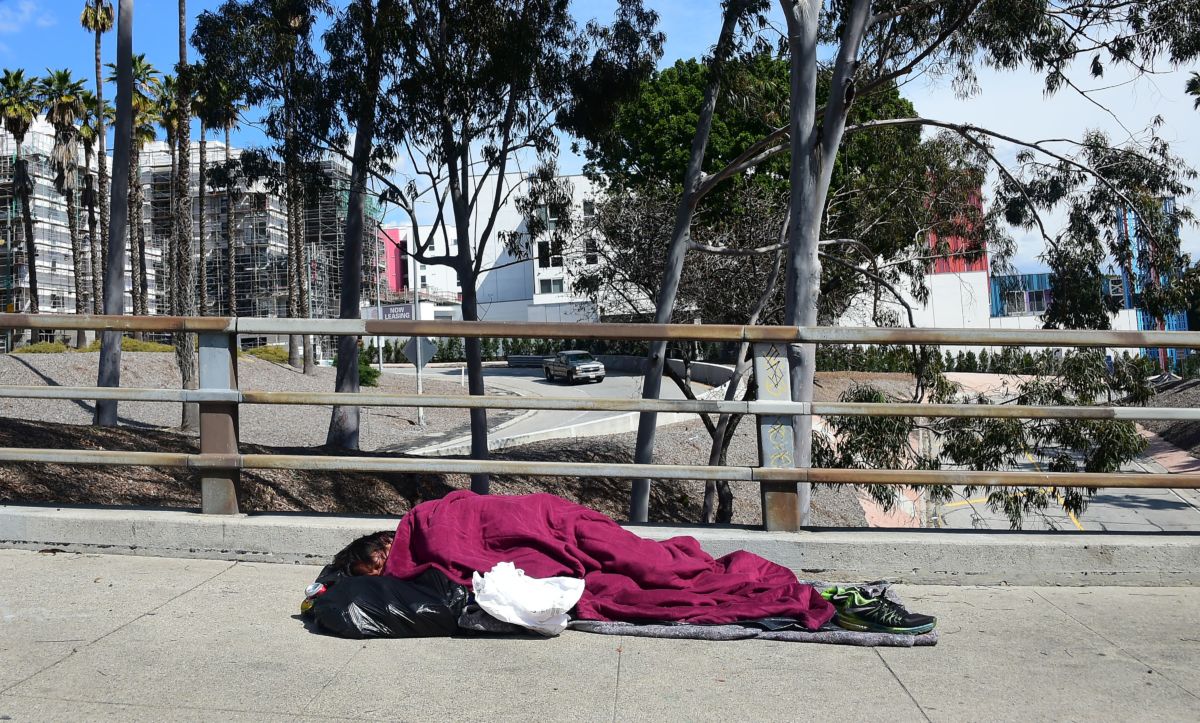 A homeless man sleeps on a sidewalk in Los Angeles, California, on March 10, 2019.