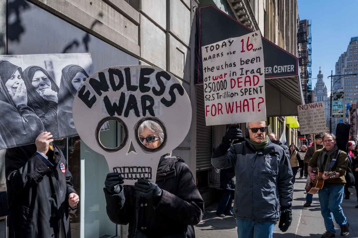 A protester displays a sign shaped like a scull that reads "Endless war"