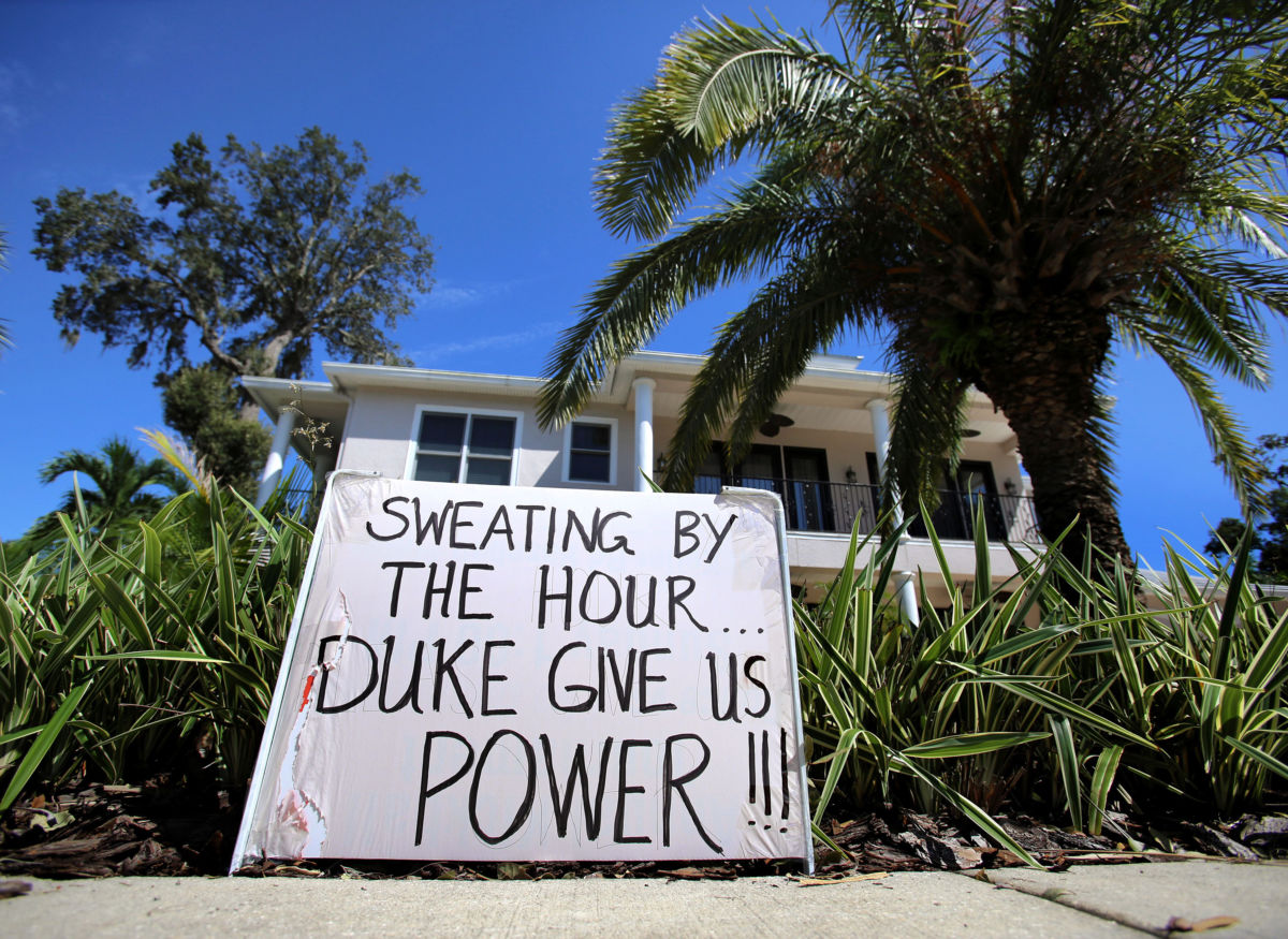 A sign outside a home reads "Sweating by the hour; Duke give us power!"