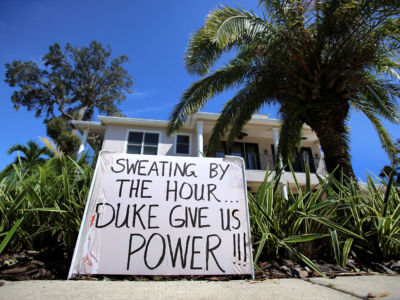 A sign outside a home reads "Sweating by the hour; Duke give us power!"