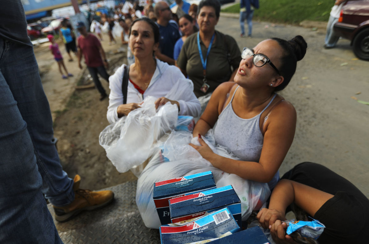 Woman recieves food as line of people still waiting stretches behind her