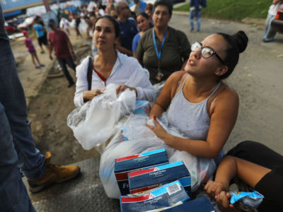 Woman recieves food as line of people still waiting stretches behind her