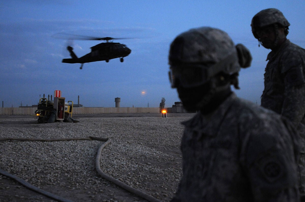 US Army soldiers look on as a Black Hawk helicopter lands at Camp Ramdi, Iraq, October 31, 2011.