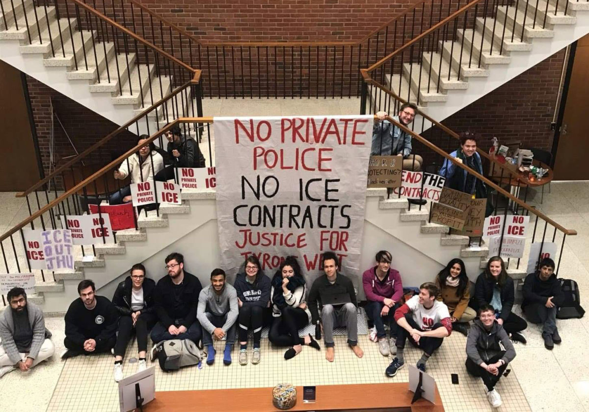 Members of Johns Hopkins Students Against Private Police and Hopkins Anti-ICE Coalition sit under a banner on April 4, 2019, in the university president's office building after sitting in overnight.