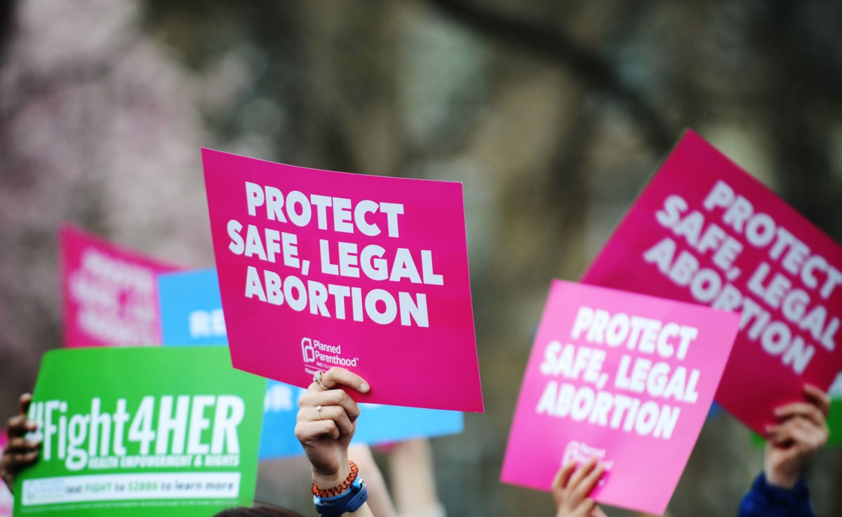 People raise signs reading Protect Safe, Legal Abortion at a pro-choice rally