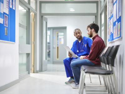 A doctor talks to a patient in a hospital waiting room