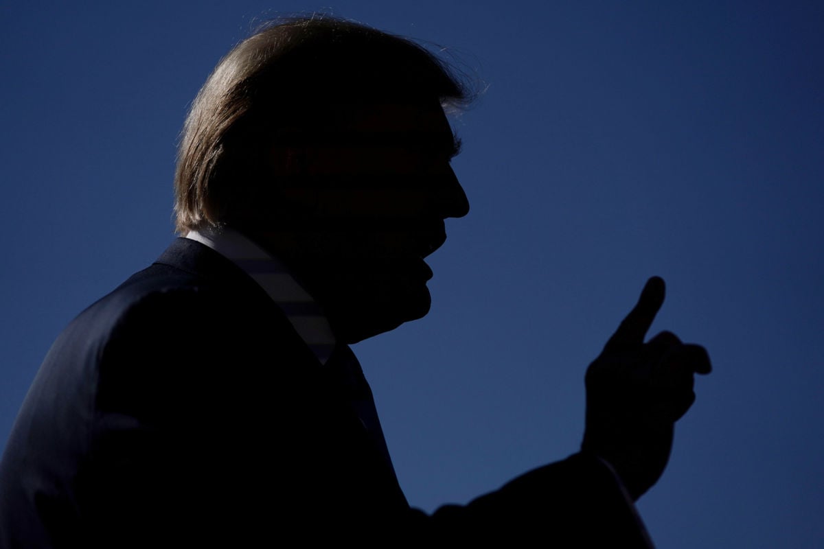 Donald Trump is silhouetted against the sky