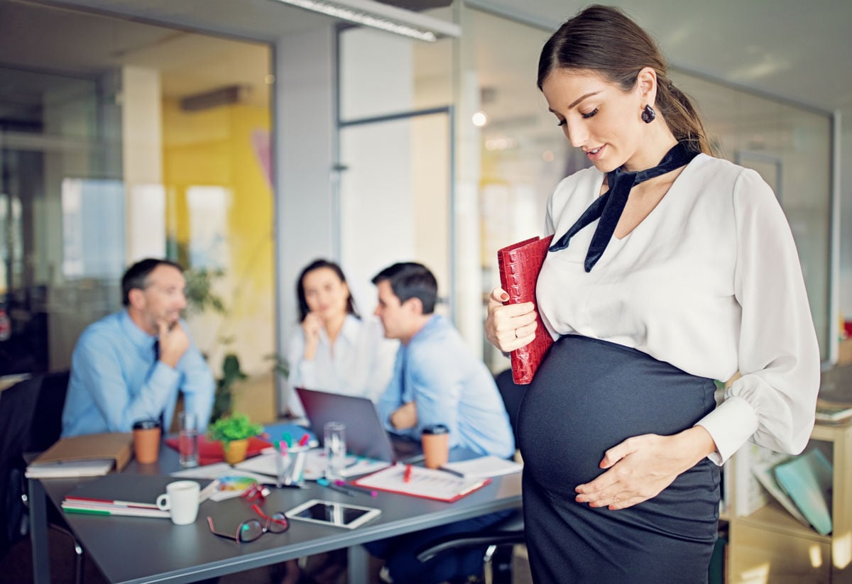 A pregnant woman stands during a business meeting