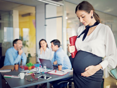 A pregnant woman stands during a business meeting