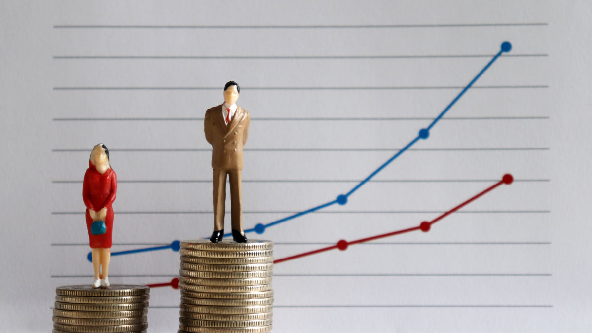 A female figure stands on a smaller stack of coins than her male counterpart