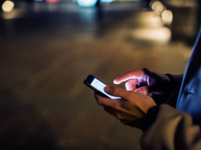 A man holds a cellphone on a darkened street