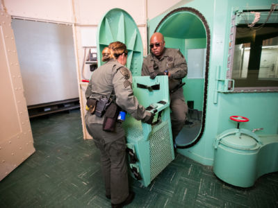Two officers dismantle the chair inside of a gas chamber