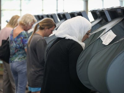 A hijabi stands at a black voting booth