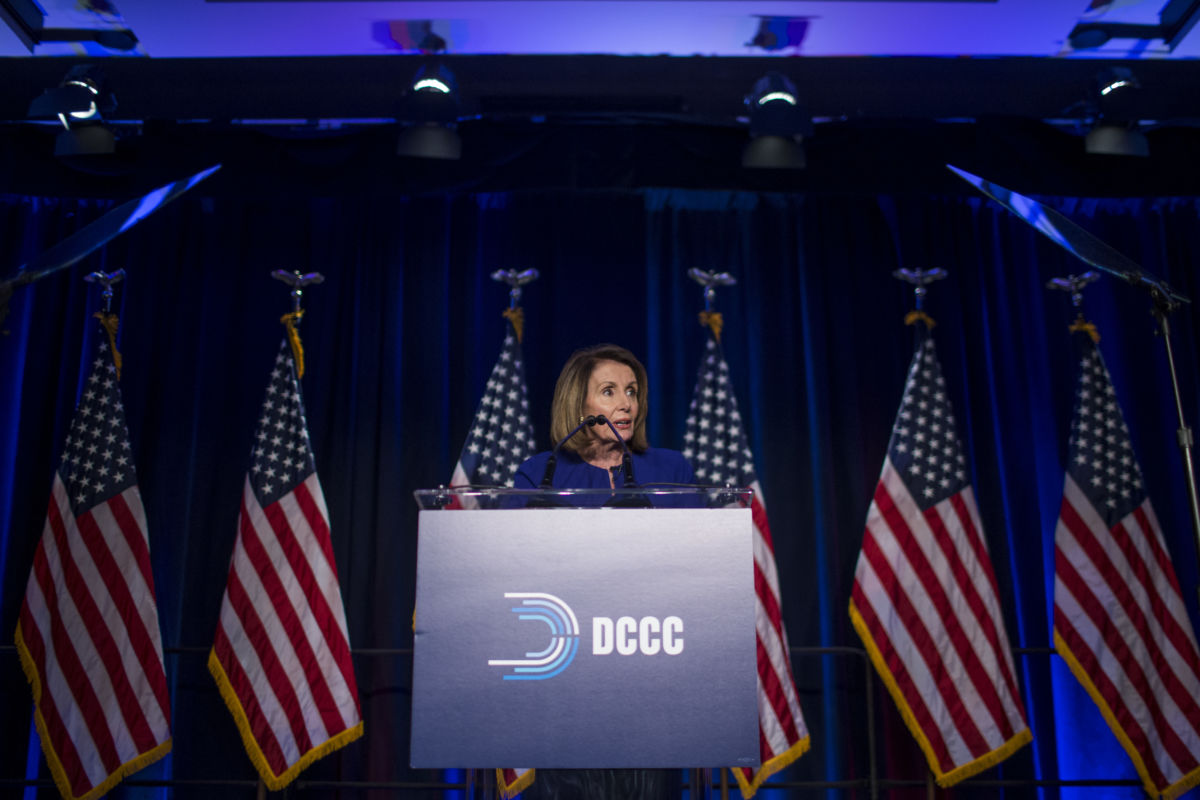 Nancy Pelosi stands at a podium that reads DCCC