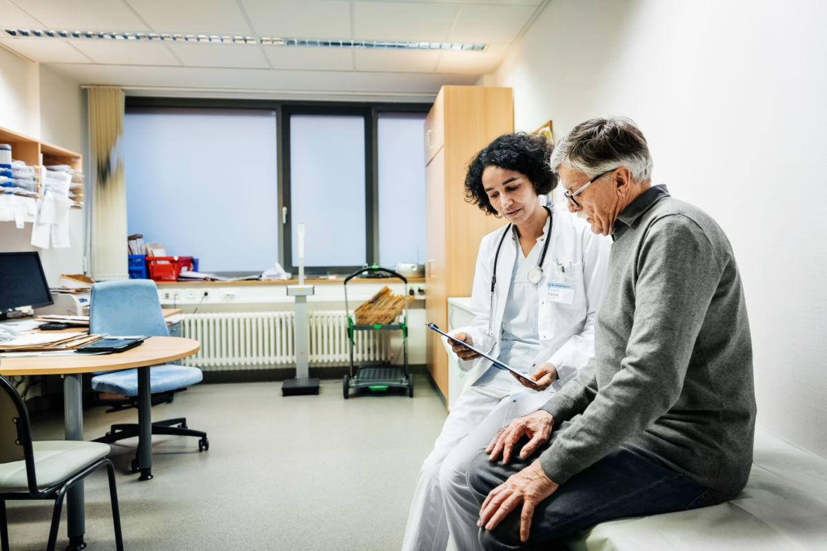 A doctor goes over forms with her elderly male patient