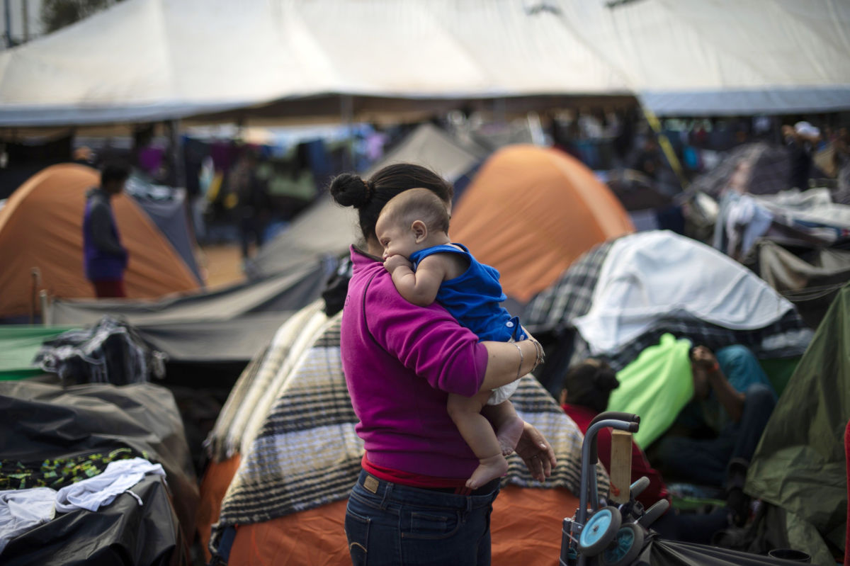 A woman holds her baby while in a refugee camp