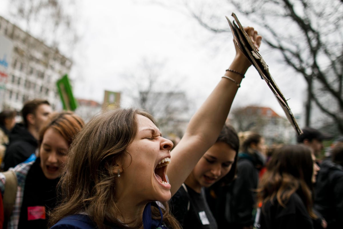 A student holds a sign and screams a chant during a rally