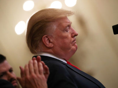 Donald Trump's face is seen in profile as he looks down at a podium