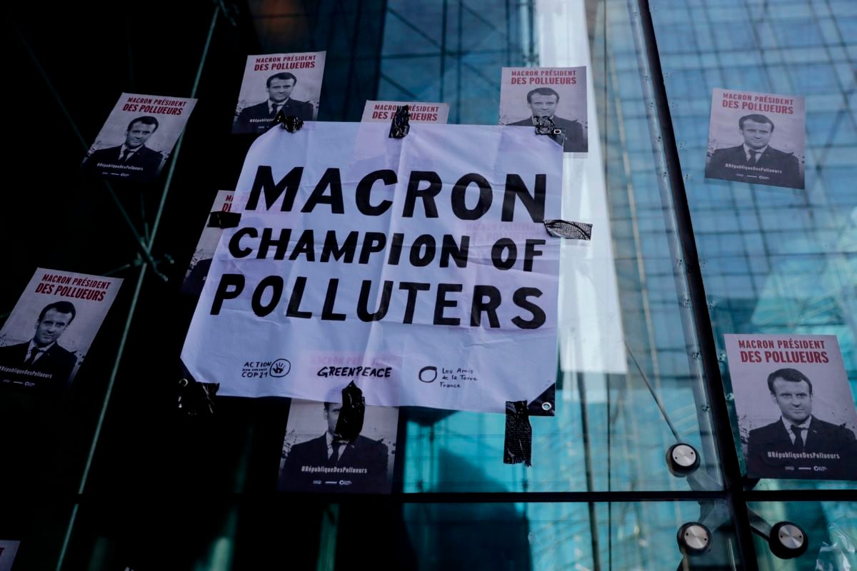 Posters displayed by Climate change activists near the entrance of the Societe Generale bank headquarters in La Defense, near Paris, depicting French President Emmanuel Macron with the words "Macron President of polluters" during an environmental protest called by the NGO Extinction Rebellion.