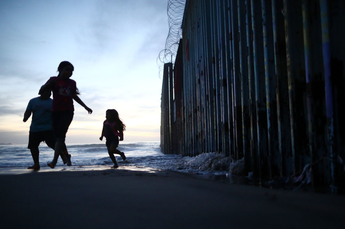 People walk near the U.S.-Mexico border on the beach on March 31, 2019, in Tijuana, Mexico.