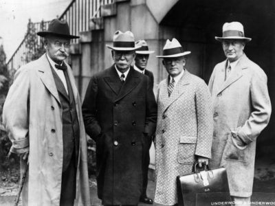 Four men in fedoras and period dress stand side by side in a black and white photo taken in 1929