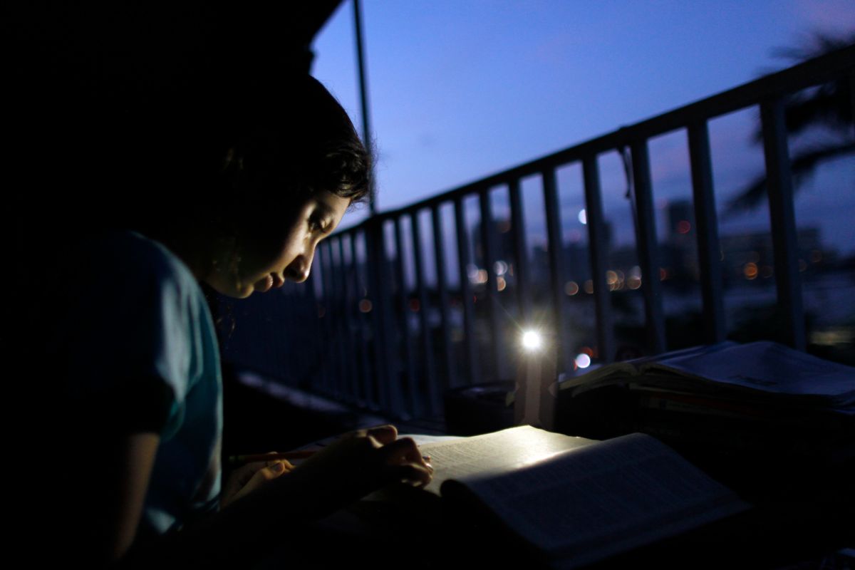 Ten-year-old Alana Rivera does her daily homework in her apartment balcony lit by a cell phone light in San Juan, Puerto Rico, November 6, 2017. Rivera's school reopened its doors without electricity to receive students 46 days after Hurricane Maria hit the island.