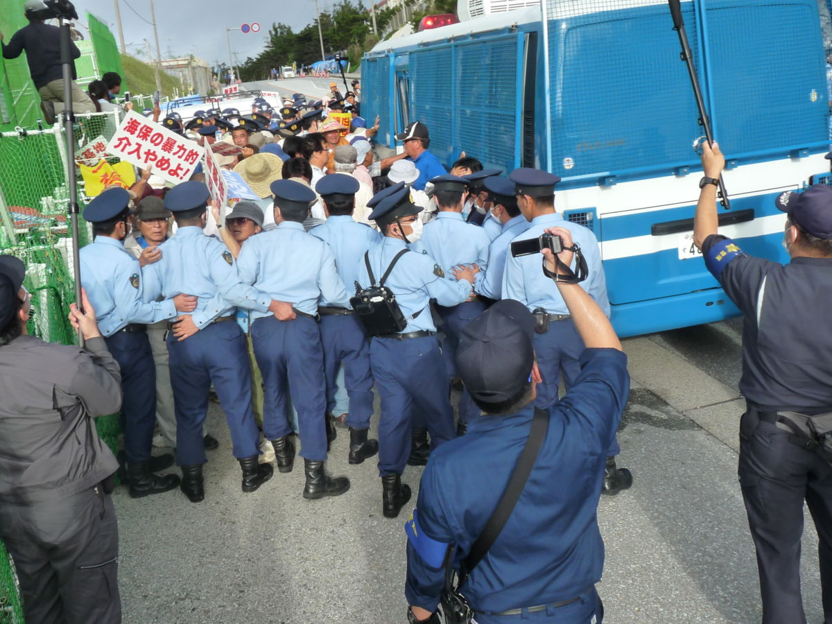 A line of police officers block protestors holding signs
