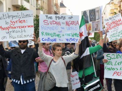 Protesters use signs to draw attention to the conflicts in Syria, Sudan and Algeria during a May Day demonstration in Berlin, Germany.