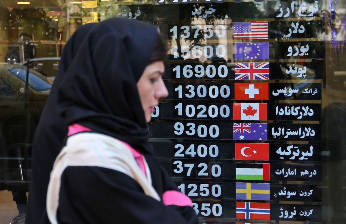An Iranian woman walks past a currency exchange shop in the capital Tehran