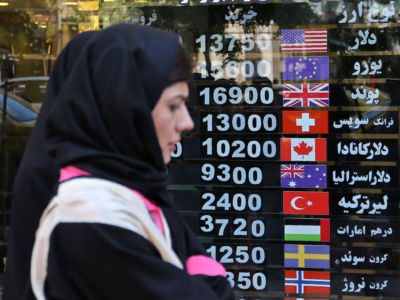 An Iranian woman walks past a currency exchange shop in the capital Tehran
