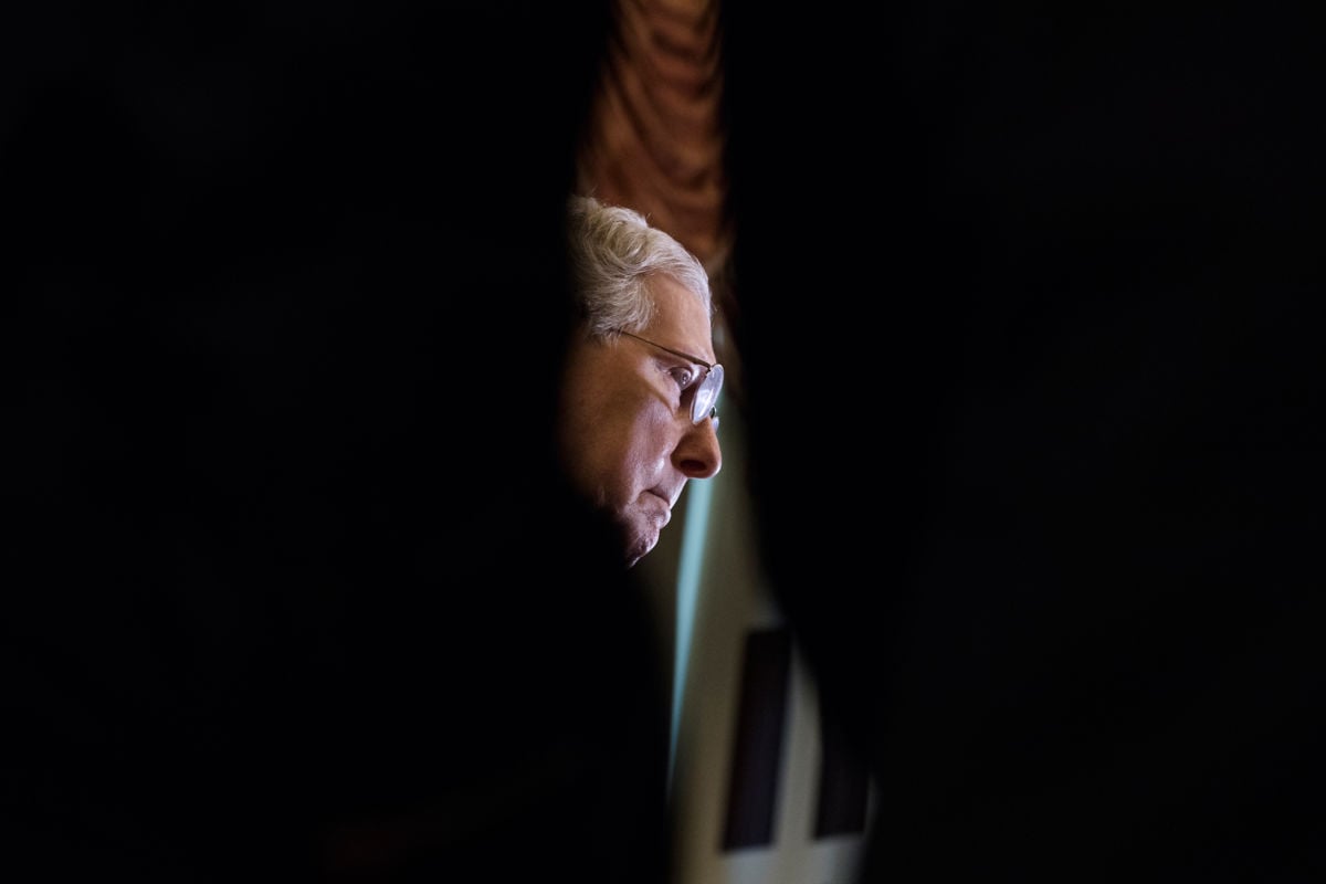 A sliver of Mitch Mcconnell's face is seen through a black foreground