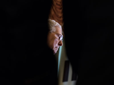 A sliver of Mitch Mcconnell's face is seen through a black foreground