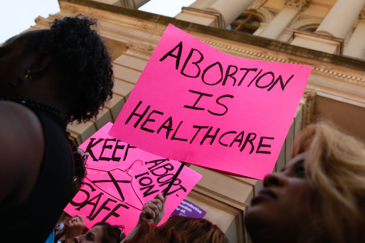 People hold signs during a protest against recently passed abortion ban bills at the Georgia State Capitol building, on May 21, 2019, in Atlanta, Georgia.