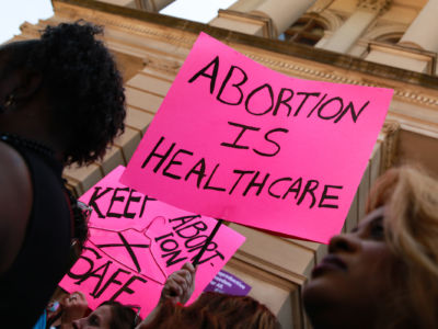 People hold signs during a protest against recently passed abortion ban bills at the Georgia State Capitol building, on May 21, 2019, in Atlanta, Georgia.
