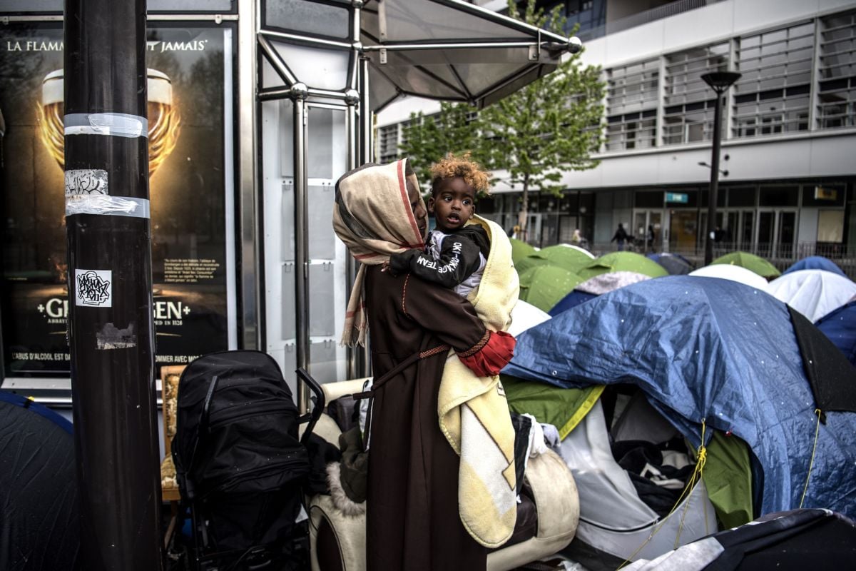 An asylum seeker holds her 1-year-old son as they stand outside their tent at a makeshift camp housing mainly families, at Porte d'Aubervilliers in Paris, France, on April 9, 2019.