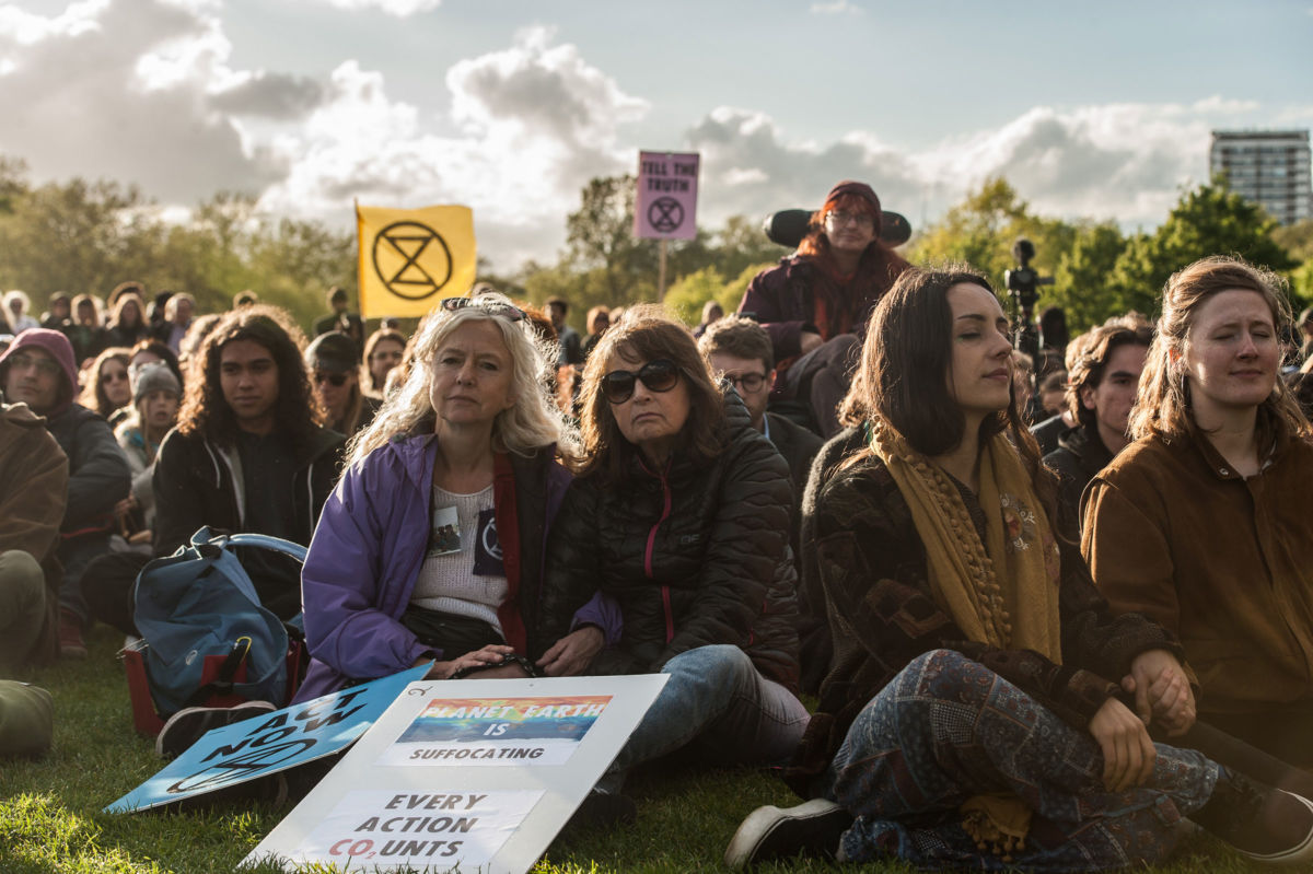 Activists listen to speeches and songs through a small PA system in Hyde Park at the closing ceremony of the Extinction Rebellion protest on April 25, 2019, in London, England.