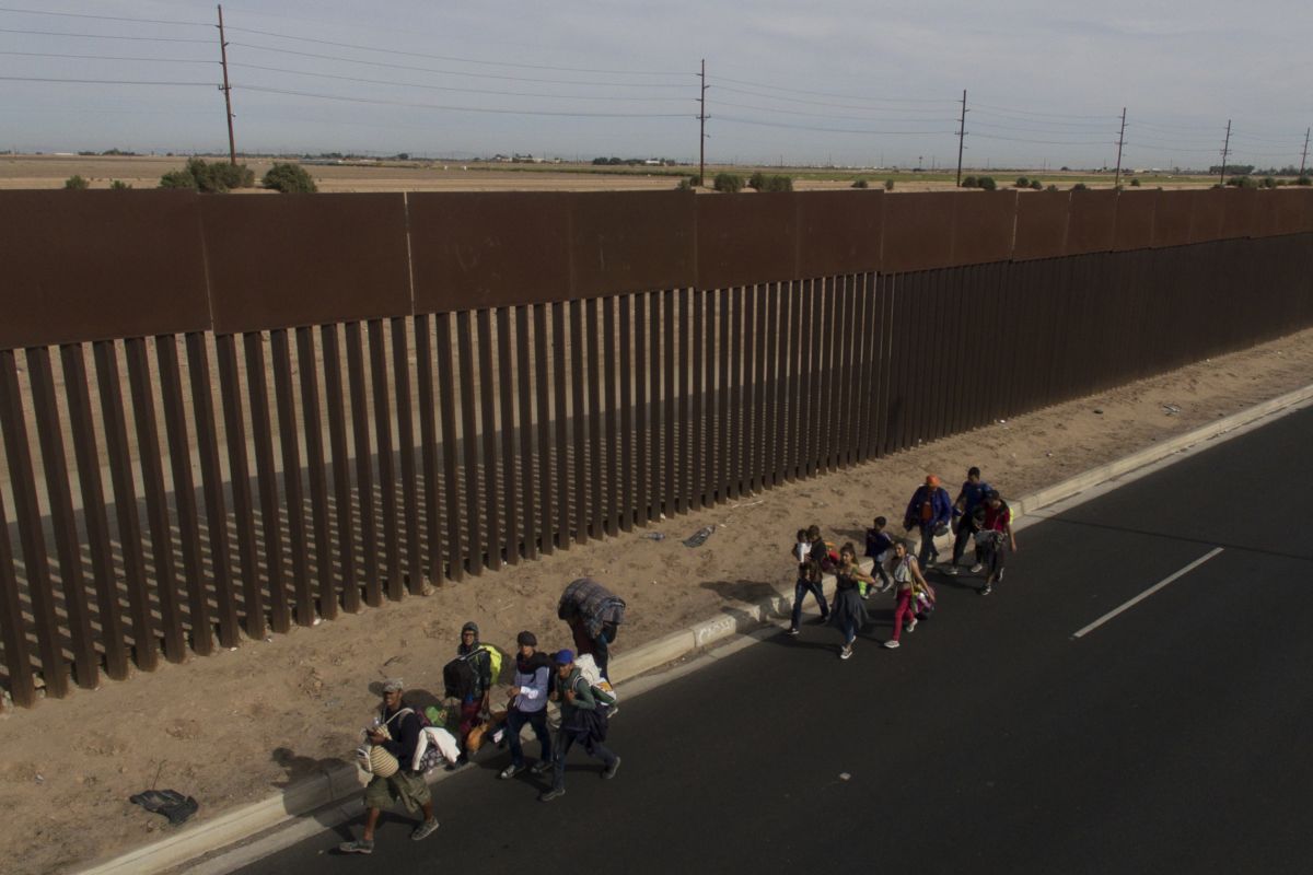 People walk alongside the border fence separating the U.S. and Mexico