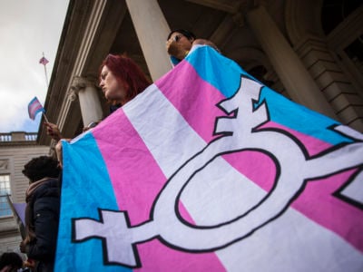 A woman holds the trans flag during a protest