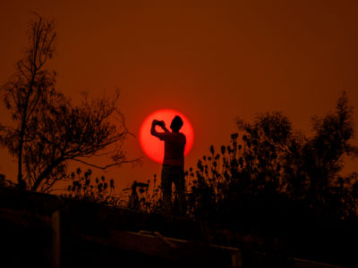 A man is silhouetted against the sun in a smoke-filled sky