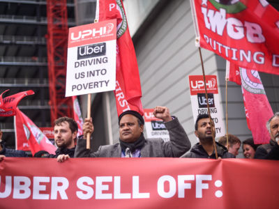 People in red protest Uber while holding pro-union signs
