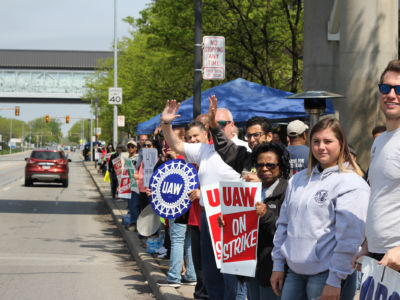 Union strikers wave towards the camera while standing in a line