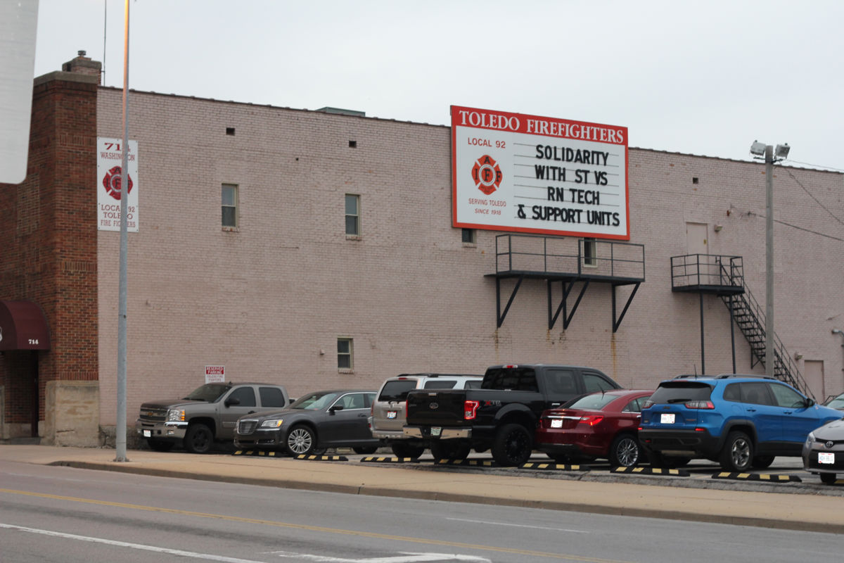 A sign is displayed on the side of a firehouse with a message of solidarity for the strikers