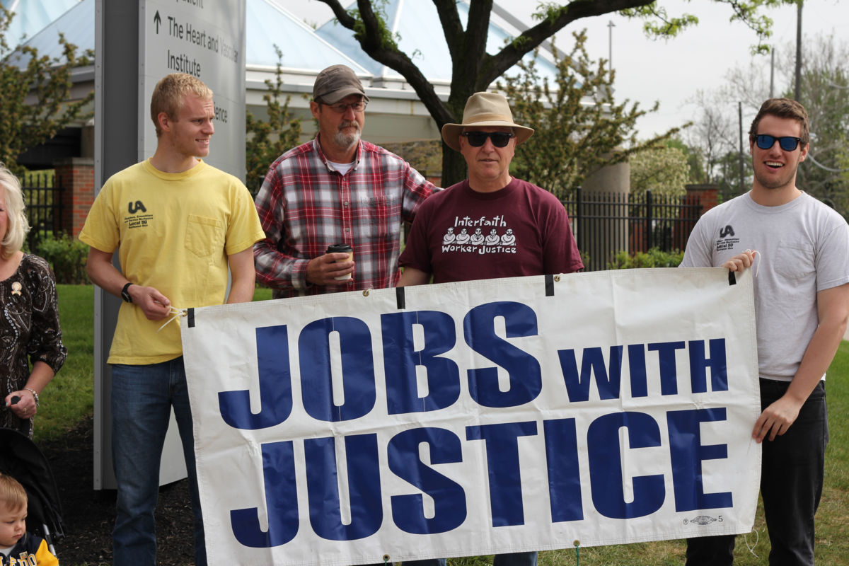 Four men display a sign reading "Jobs with justice"