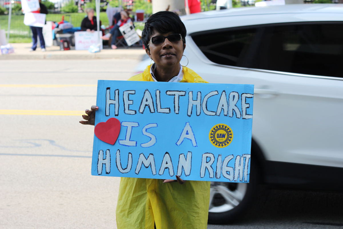 A strike supporter holds a sign declaring "Health care is a human right."